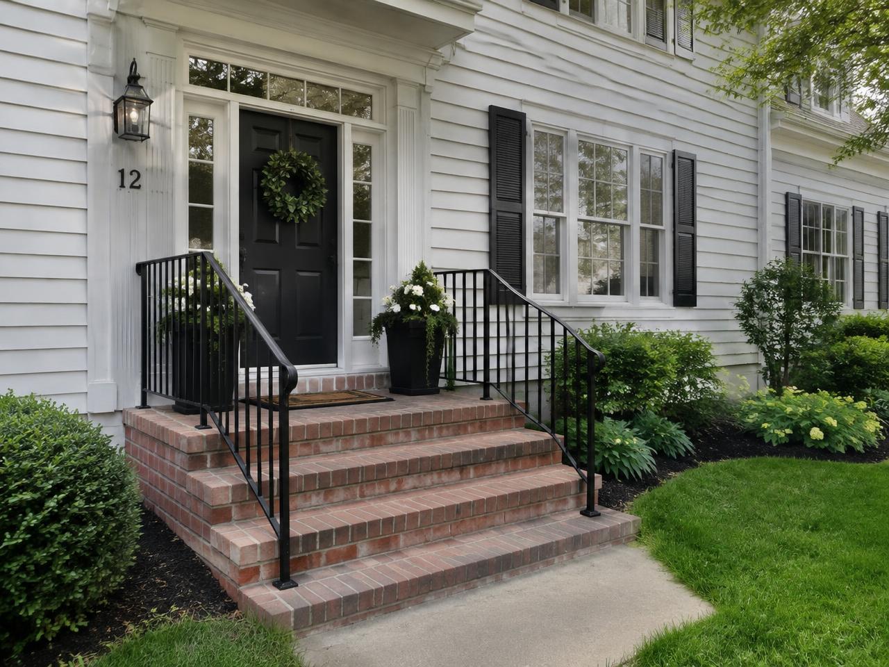 Black exterior railing on brick front steps of a colonial home